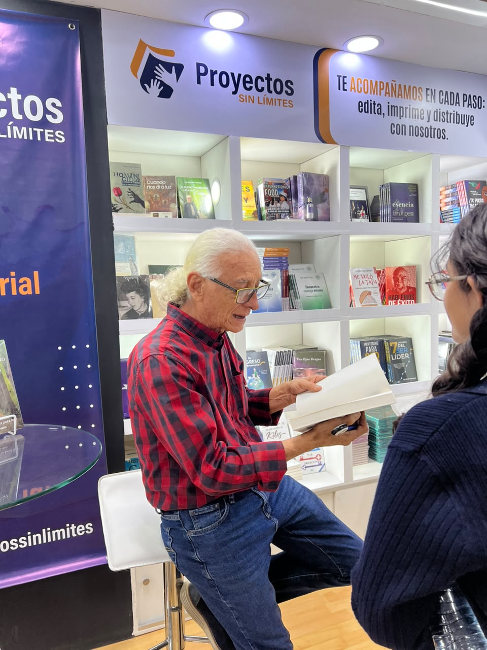 Banner principal del stand de Proyectos Sin Limites con estanteria de libros en la FILBO 2026